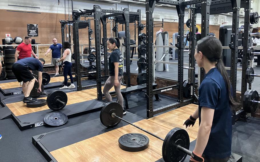 People in exercise clothing use weights in a gym.