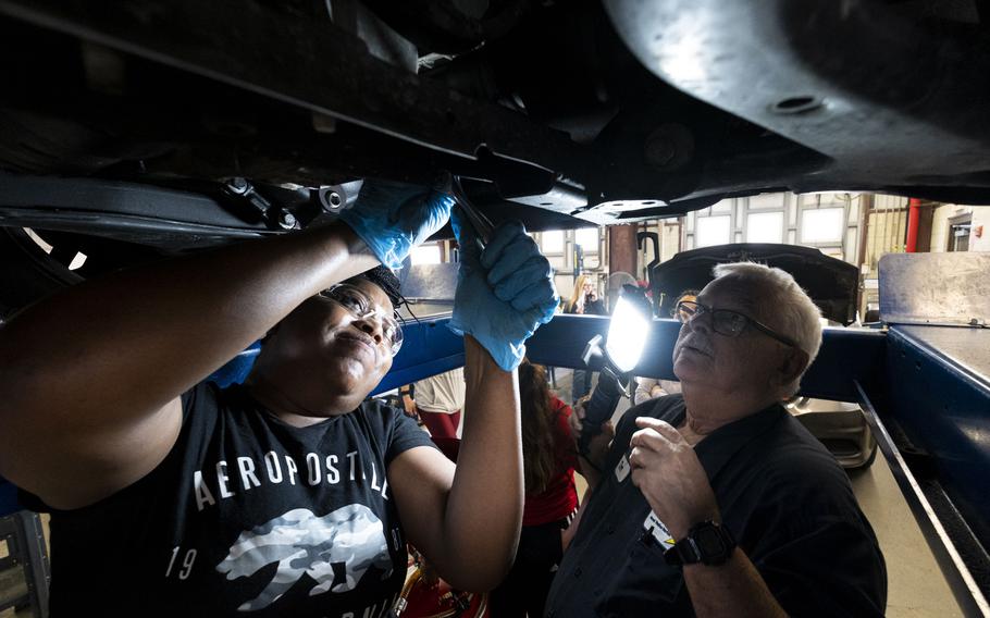 Tim Daubert, left, instructs Alliyah Moore on how to change oil in her car at the Naval Station Norfolk Auto Skills building in Norfolk, Va., on March 24, 2023. The class is designed for women who want to learn how to conduct basic maintenance on their vehicles.