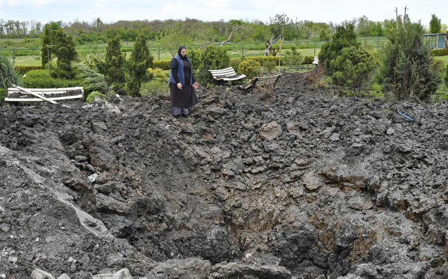 Orthodox Sister Evdokia gestures in front of the crater of an explosion, after Russian shelling next to the Orthodox Skete in honor of St. John of Shanghai in Adamivka, near Slovyansk, Donetsk region, Ukraine, Tuesday, May 10, 2022.