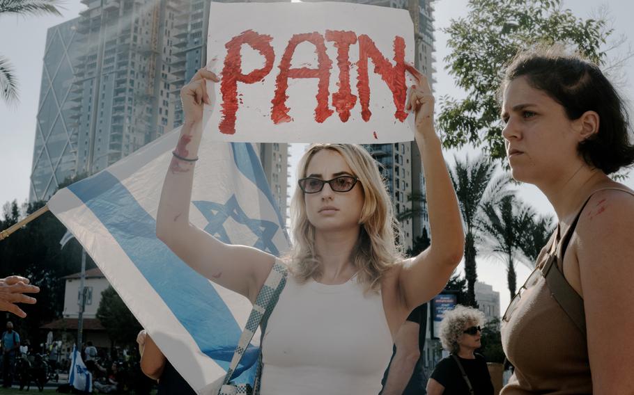 An Israeli woman holds a sign that reads “Pain” during a protest Oct. 14, 2023, in Tel Aviv for the release of hostages. 