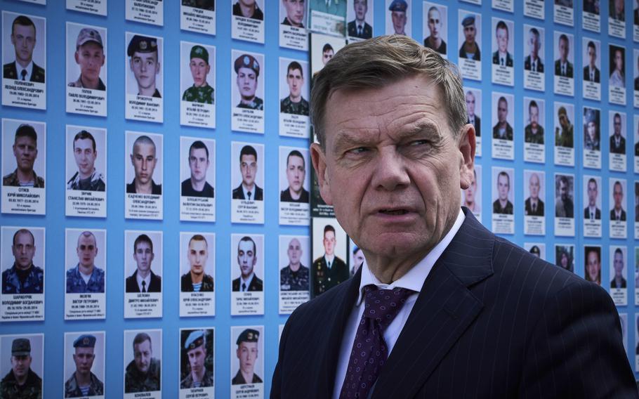 Wadephul stands in front of a memorial that shows photos of fallen Ukrainians.