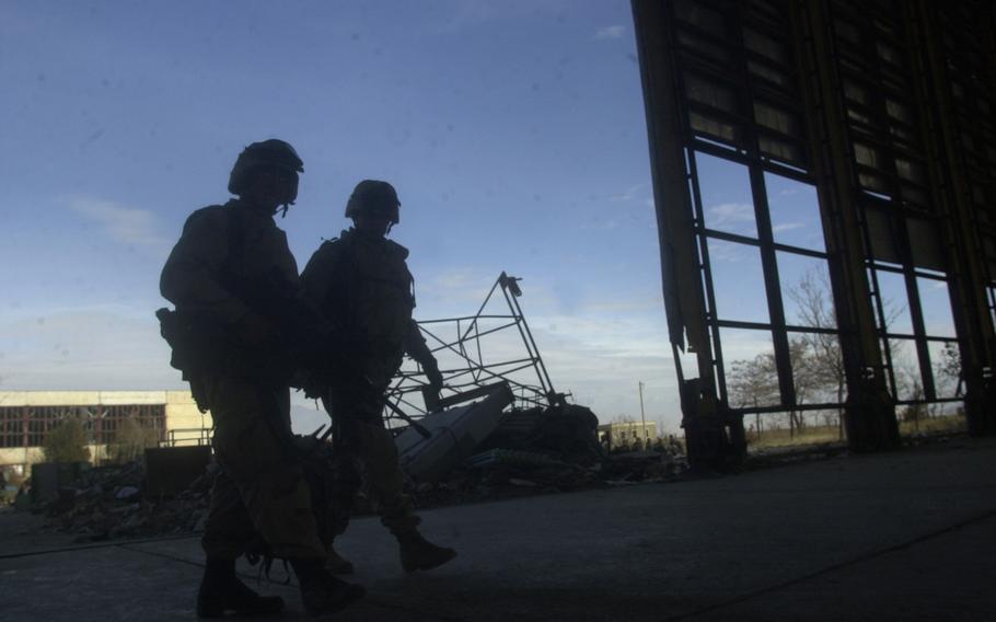 A pair of 10th Mountain Division soldiers patrol through a recently cleared out hangar on Bagram Airfield in Afghanistan, in December 2001. The U.S. has fully withdrawn from the airfield, once the largest American base in the country, a U.S. defense official confirmed Friday.   