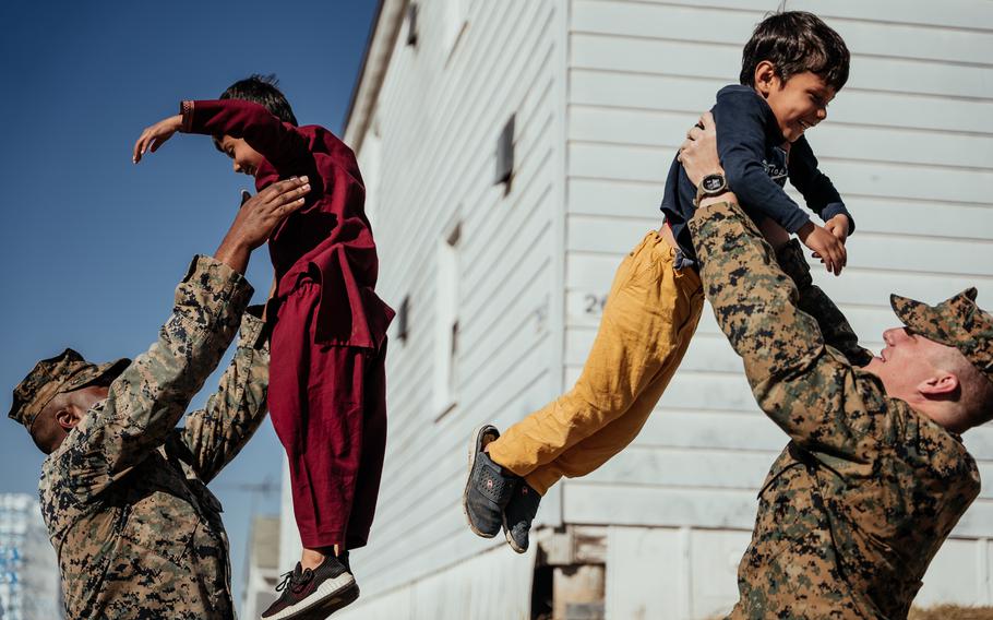 Marine Corps Cpl. Christophe Strickland (left), and Cpl. Ethan Gentry (right), both mortarmen with 1st Battalion, 23rd Marine Regiment, play with Afghan children on Fort Pickett, Va., on Nov. 18, 2021. 