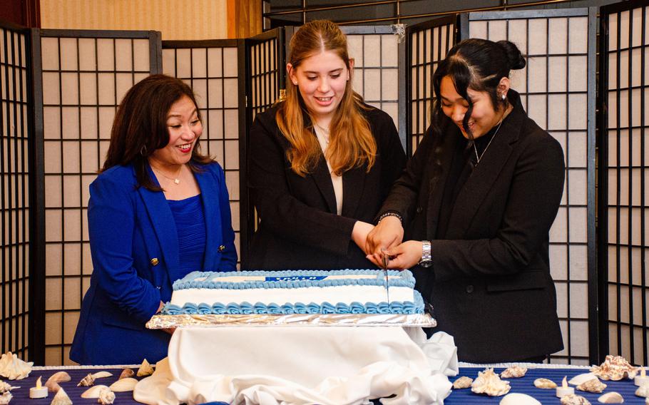Bailee McCollum, center, and Jazlynn Lorenzo cut their cake at the Asia Military Youth of the Year Award ceremony at Yokosuka Naval Base, Japan, March 31, 2023.