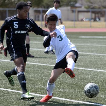 Robert D. Edgren's Patrich Lorenzo boots the ball away from Zama's Alec Carter during Saturday's DODEA-Japan soccer match. The Trojans edged the Eagles 4-3.