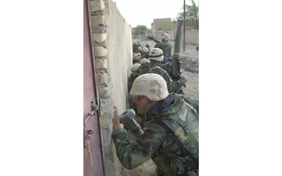 Every wall is a shelter and possible ambush site. A Marine peers through a crack in a door frame to ensure Baath Party irregulars aren’t trying to outflank the Marines.  