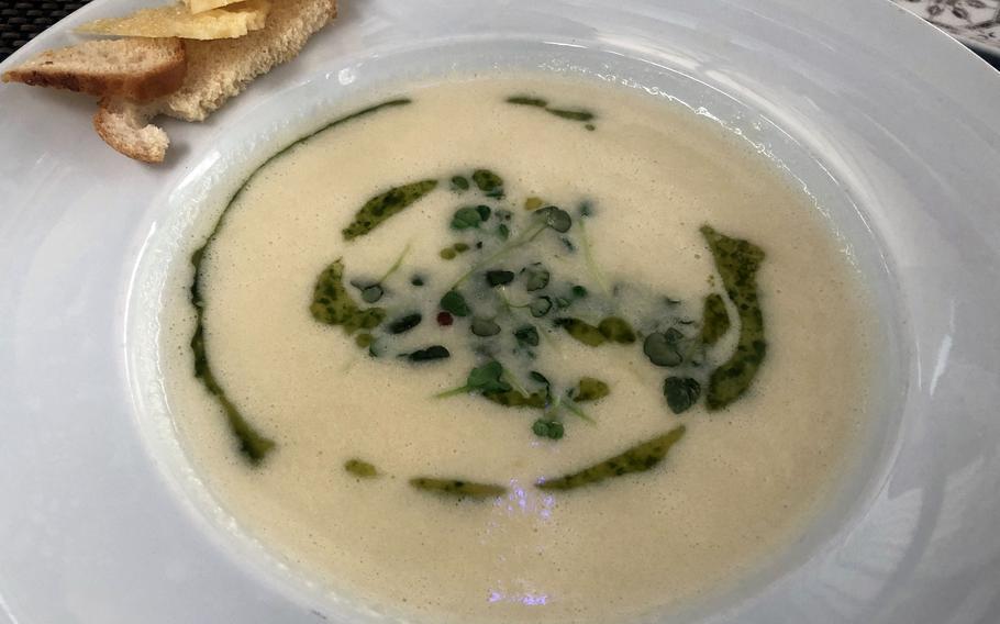 The Parmesan soup at Lumen in Wiesbaden is served with a swirl of basil pesto and cress, and baguette slices and Parmesan chips on the side.