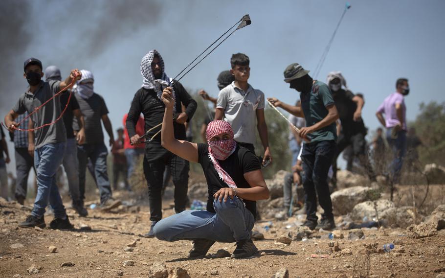 Palestinian demonstrators use slingshot to hurl stones towards Israeli security forces during a protest against the West Bank Jewish outpost of Eviatar that was rapidly established last month, at the Palestinian village of Beita, near the West Bank city of Nablus, Friday, July 2, 2021.