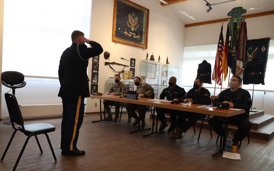An Army sergeant stands and salutes before a seated panel.