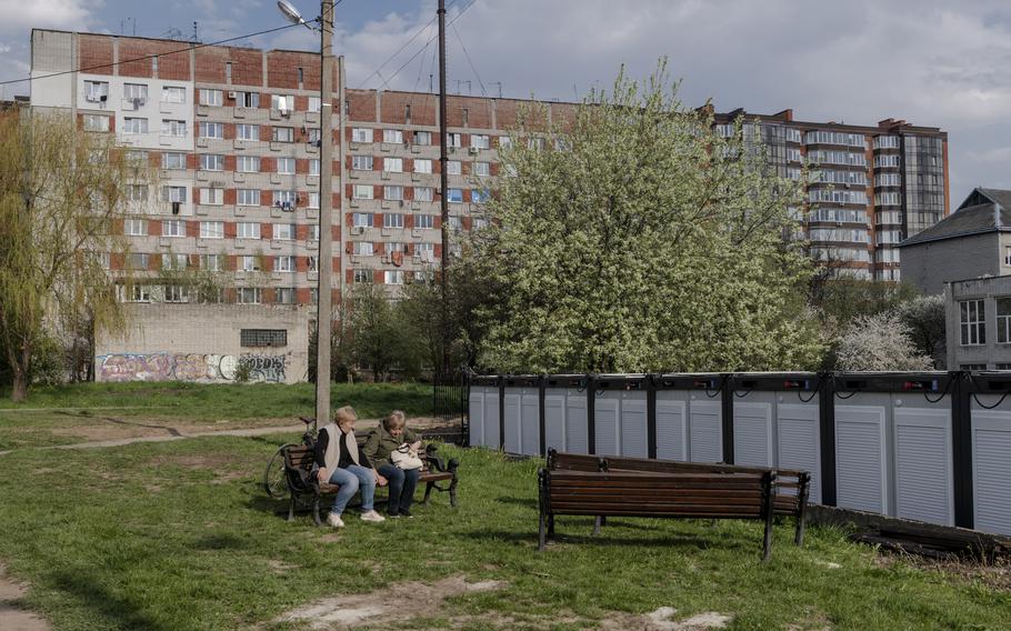 Two women sit on a bench near temporary modular houses in Lviv on May 2. 