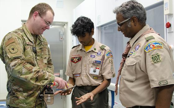 Staff Sgt. John Mullaney II, a scientific applications specialist at the U.S. Air Force Radiochemistry Lab at Patrick Space Force Base, Fla., uses an Alpha/Beta Survey Meter to check for potential contamination on the hands of Tejeshwar Umamaheswar, a Boy Scout from Troop 263 in Lake Mary, Fla., as his father and Scout Master, Umamaheswar Kasinathan, looks on. Teja was one of 62 scouts who traveled to the Air Force Technical Applications Center Oct. 22, 2022 to earn the Nuclear Science Merit Badge with help from Airmen who work at the Department of Defense’s sole nuclear treaty monitoring center.