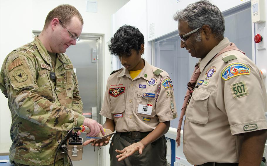 Staff Sgt. John Mullaney II, a scientific applications specialist at the U.S. Air Force Radiochemistry Lab at Patrick Space Force Base, Fla., uses an Alpha/Beta Survey Meter to check for potential contamination on the hands of Tejeshwar Umamaheswar, a Boy Scout from Troop 263 in Lake Mary, Fla., as his father and Scout Master, Umamaheswar Kasinathan, looks on. Teja was one of 62 scouts who traveled to the Air Force Technical Applications Center Oct. 22, 2022, to earn the Nuclear Science Merit Badge with help from Airmen who work at the Department of Defense’s sole nuclear treaty monitoring center.