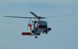 A helicopter flies into a blue sky.