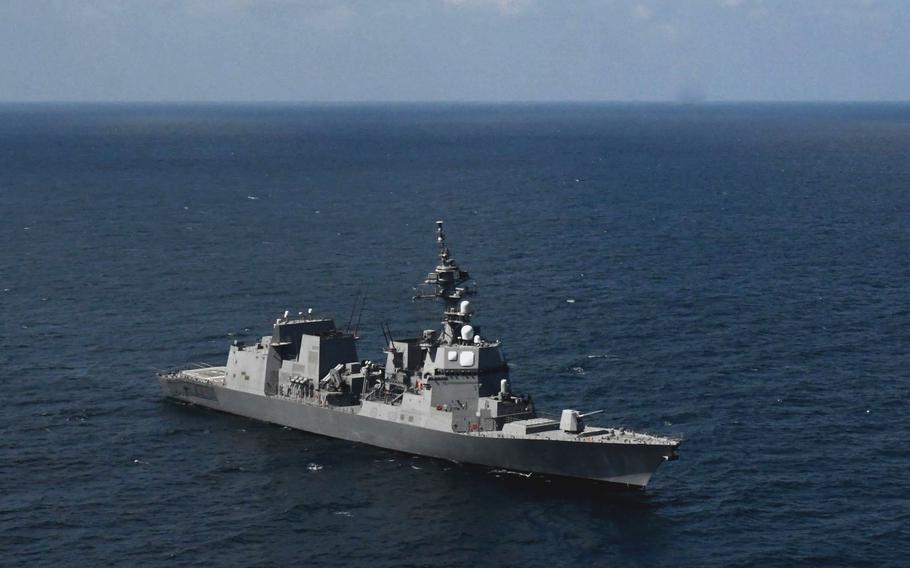 A modern naval destroyer with hull number 117 sails through deep blue ocean waters under a partly cloudy sky. .