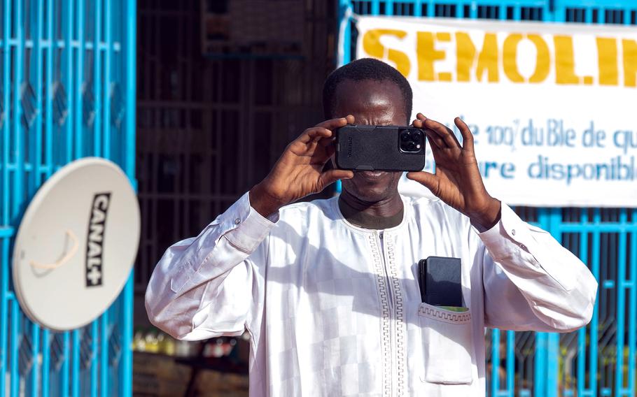 A man takes a cellphone photo in Niamey, Niger, on May 6, 2023. Russia is driving a surge of disinformation campaigns in Africa, according to a report this month from a Pentagon-linked think tank. The campaign includes paid African influencers, digital avatars and the circulation of fake videos and photographs, researchers said.