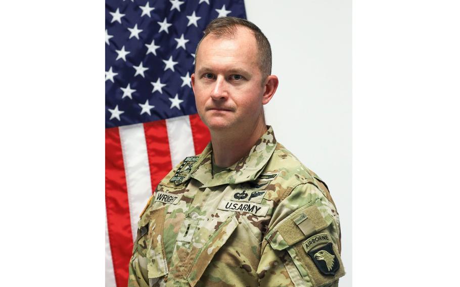 A soldier poses for a photo in front of an American flag