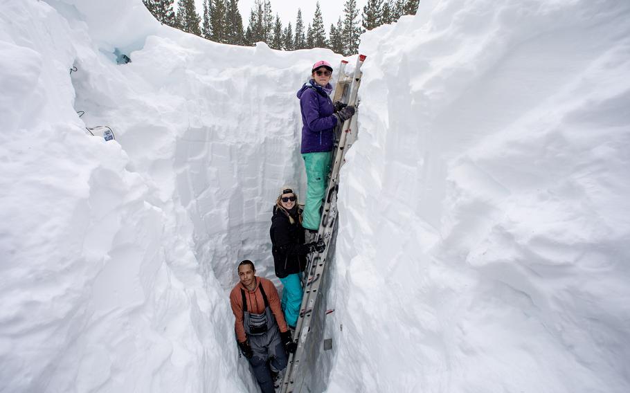 Working inside a nearly 18-foot-deep snow pit at the UC Berkeley Central Sierra Snow Lab, Shaun Joseph, l-r, Claudia Norman and Helena Middleton take measurements of snow temperatures ahead of an atmospheric weather storm, March 9, 2023, in Soda Springs, Calif.