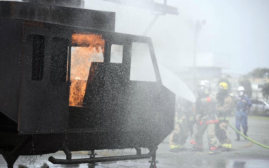 Firefighters work to extinguish flames from a simulated helicopter crash during a major accident response exercise at Yokota Air Base in western Tokyo, May 11, 2022. 