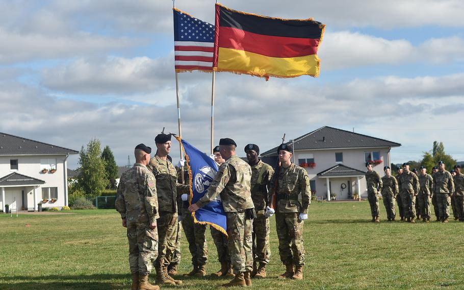 Command Sgt. Maj. Michael Carlan unfurls the flag of a new task force, which was activated at a ceremony on Clay Kaserne in Wiesbaden, Germany, on Sept. 16, 2021. 