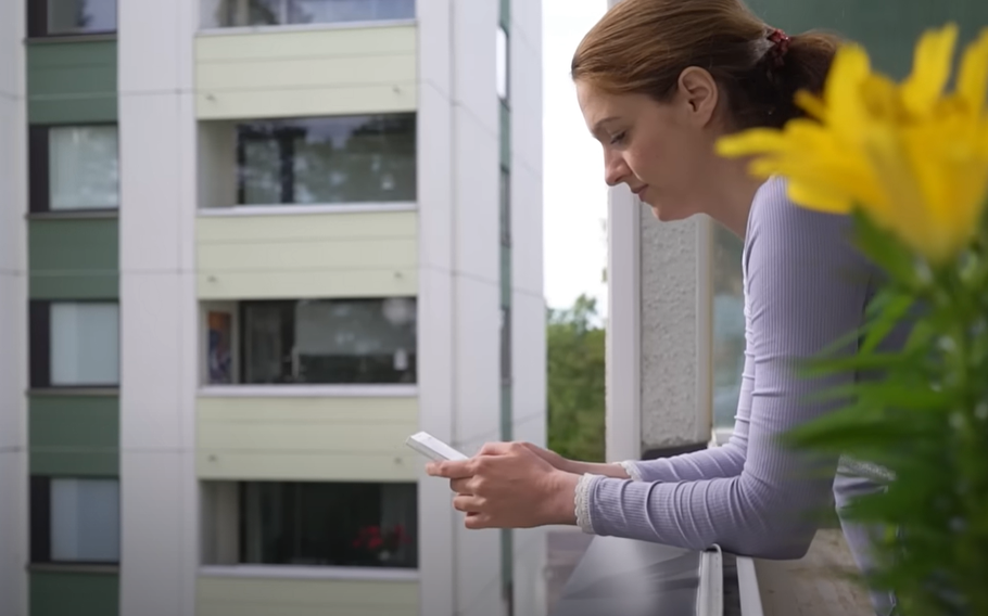 A woman looking at her phone on a balcony