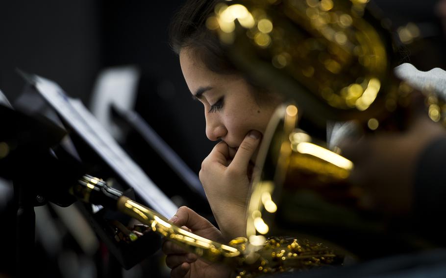 A close-up view of a woman next to musical instruments looking down with her hand on her chin.