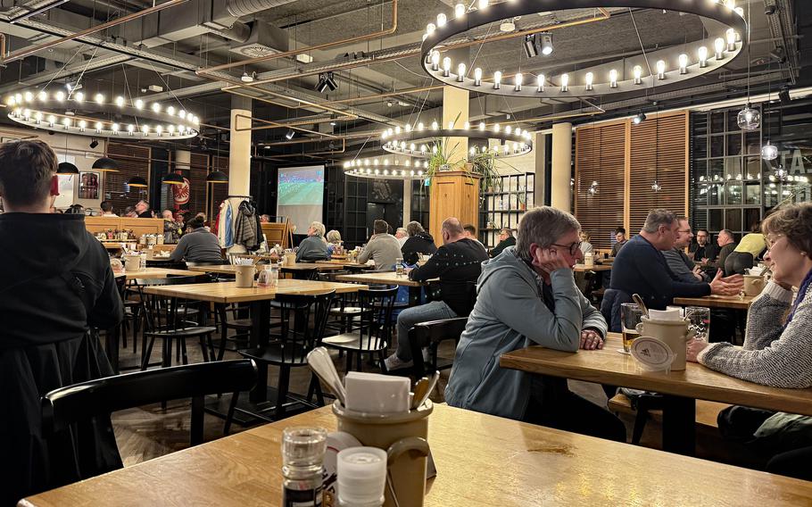 A table in the foreground and people eating and talking in the background.