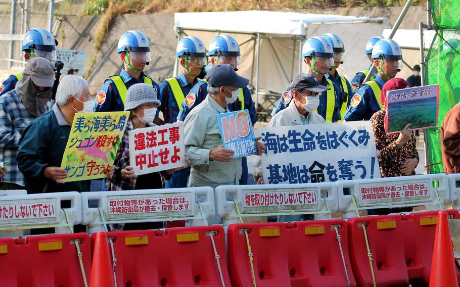 Protesters hold signs in Okinawa, Japan, on Feb. 21, 2024. Increased military tensions around Taiwan are raising the pressure on neighboring islands such as Japan, which in anticipation of potential conflict, has bolstered its defense spending. But those plans have met civilian opposition, most notably in Okinawa, home to numerous U.S. military bases and likely one of the first targets in the event of a clash with China.