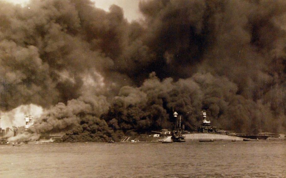 A view of “Battleship Row” during or immediately after the Japanese raid on Pearl Harbor, Dec. 7, 1941. The capsized USS Oklahoma (is in the center, alongside USS Maryland.