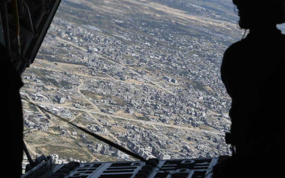 An airman on a U.S. Air Force C-130 cargo plane gazes out at the rubble in northern Gaza after the end of a humanitarian airdrop mission on Wednesday, March 20, 2024. 