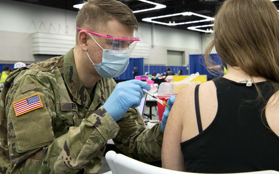 An Oregon Army National Guard medic administers the COVID-19 vaccine during a mass vaccination clinic at the Oregon Convention Center, Portland, Ore., April 19, 2021. 