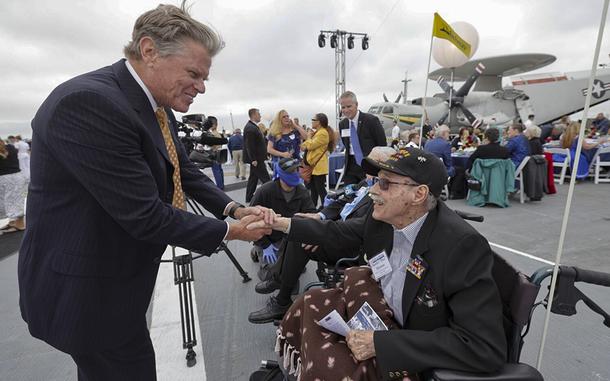 SAN DIEGO, CA - JUNE 4, 2022: President and CEO of the USS Midway Museum Mac McLaughlin shakes hands with Battle of Midway veteran Aviation Radioman First Class Charles Monroe, 98, before the start of the commemoration ceremony of the 80th anniversary of the Battle of Midway and the Centennial of U.S. Navy Aircraft Carriers at the USS Midway Museum in San Diego on Saturday, June 4, 2022. (Hayne Palmour IV / For The San Diego Union-Tribune)