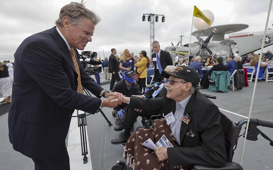 President and CEO of the USS Midway Museum Mac McLaughlin shakes hands with Battle of Midway veteran Aviation Radioman First Class Charles Monroe, 98, before the start of the commemoration ceremony of the 80th anniversary of the Battle of Midway and the Centennial of U.S. Navy Aircraft Carriers at the USS Midway Museum in San Diego on June 4, 2022. 