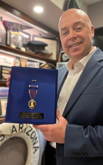 A man poses with a Purple Heart medal
