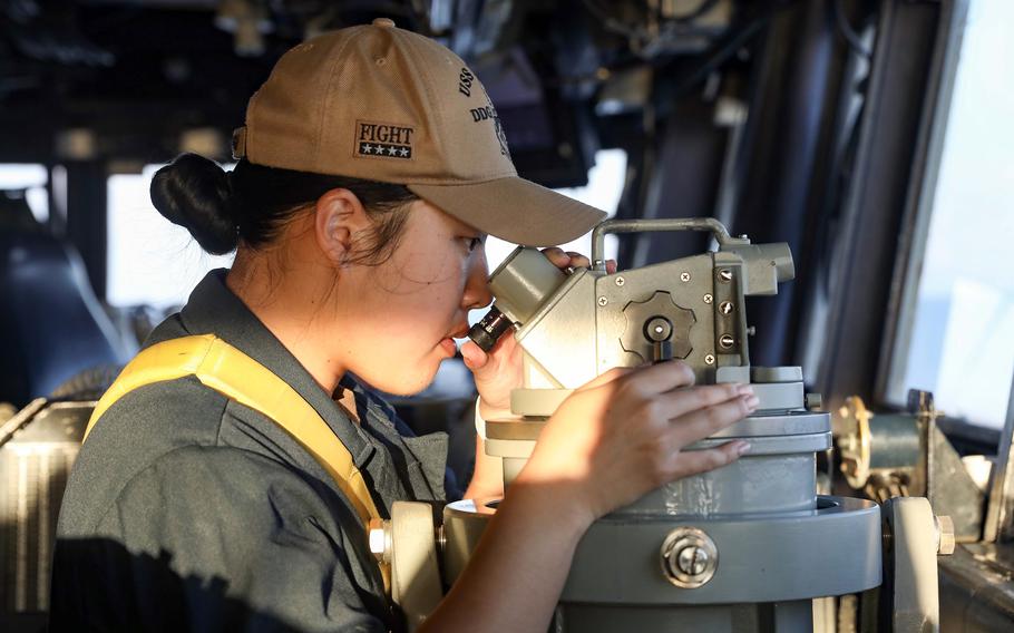 Ensign Nicole Choi looks through a telescopic alidade as the guided-missile destroyer USS Dewey sails near the Spratly Islands in the South China Sea, Friday, Nov. 3, 2023. 