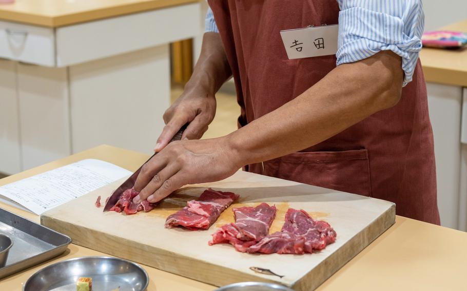 Masahiro Yoshida slices beef for the stroganoff that he and other students — all men, all seniors —are making in their class in Tokyo.  Yoshida recently agreed to share meal prep with his wife. 