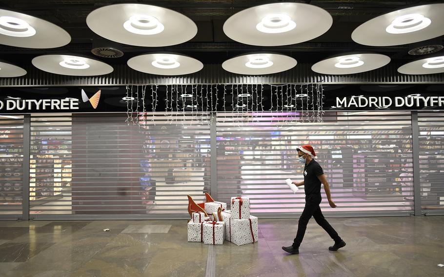 An airport employee walks through a Christmas gifts at the Adolfo Suárez Madrid Barajas International Airport on Dec. 31, 2021, in Madrid, Spain. 