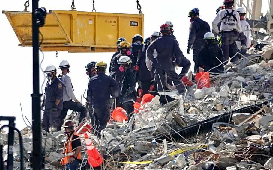 A bucket brigade works to remove debris from the Champlain Towers South Condo collapse on Monday, June 28, 2021, in Surfside, Fla. 