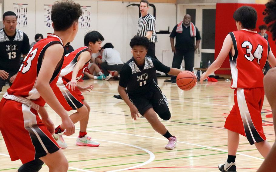 Zama's Casey Armstrong dribbles through St. Maur defenders during Wednesday's Kanto Plain boys basketball game. The Trojans beat the Cougars 77-22.