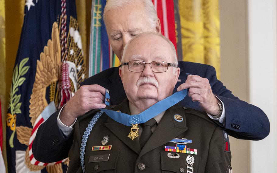 Joe Biden places the Medal of Honor around the neck of an elderly man in military dress uniform.