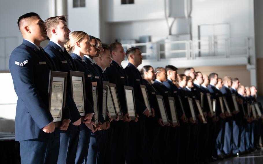 U.S. Airmen and recipients of the Distinguished Flying Cross hold copies of their congressional record during a ceremony at Travis Air Force Base, California, Dec. 9, 2022. U.S. Air Force Maj. Gen. Corey Martin, 18th Air Force commander, recognized 24 Airmen for their heroic actions during Operation Allies Refuge. The Distinguished Flying Cross is awarded to any officer or enlisted person of the U.S. armed forces for heroism or extraordinary achievement while participating in aerial flight.