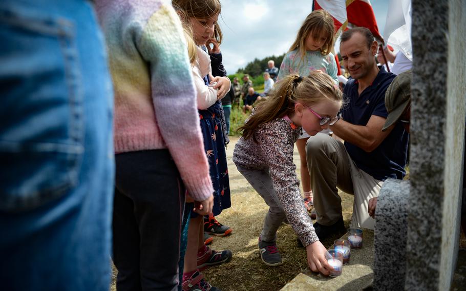 A young girl places a memorial candle on a stele commemorating the landing of Operational Group PAT during World War II, during a ceremony near Berlats, France, May 27, 2022. OG PAT helped French resistance fighters free the region from Nazi occupation in 1944. 