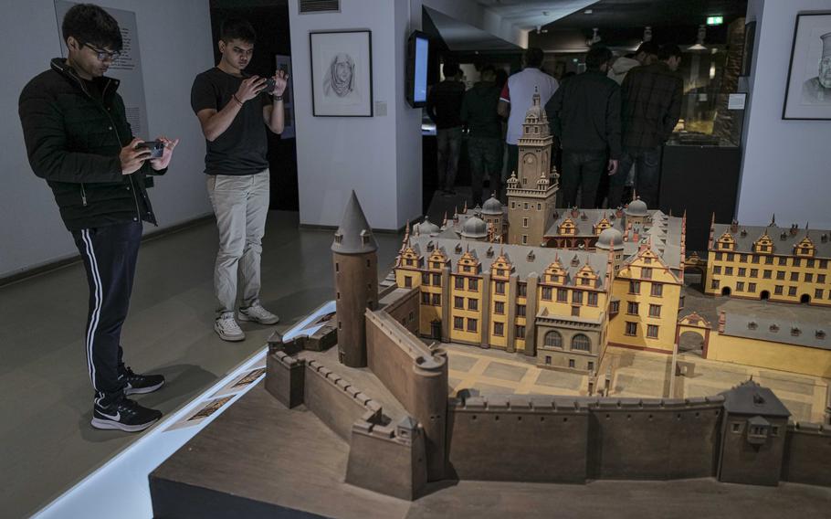 Visiting students photograph a model of Saarbruecken Castle, including its red tower, at the Saar Historical Museum in Saarbruecken, Germany, on Oct. 19, 2023. The model highlights the architectural evolution of the castle, which has evolved from medieval fortifications into a baroque palace over time.