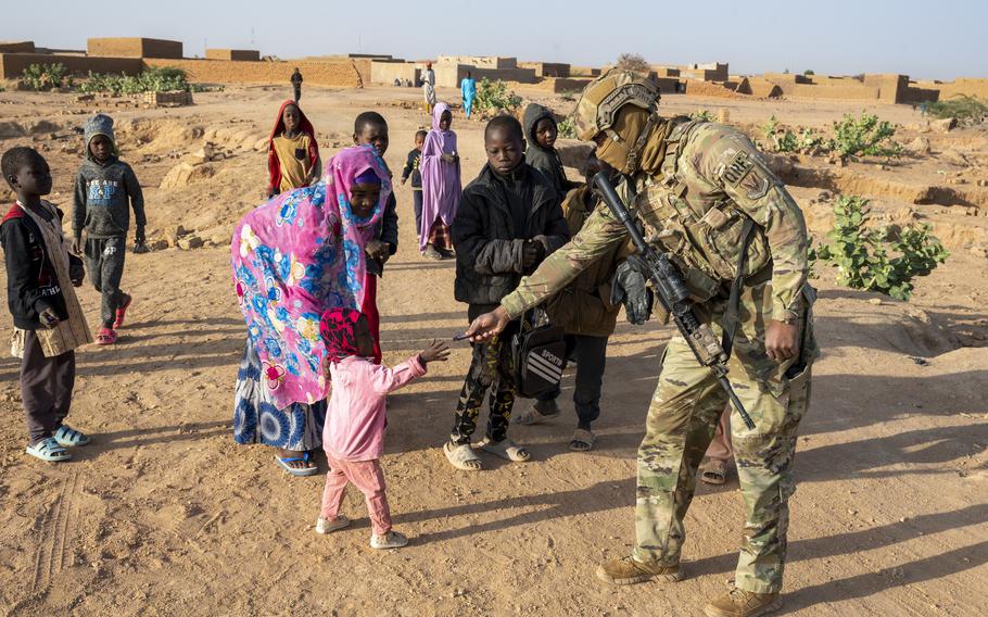 Air Force Senior Airman Lorenzo Bennette offers candy to a child near Base 201 in Niger on Jan. 6, 2023. The more than 1,000 American service members in Niger will stay there for the time being amid efforts to restore the democratically elected leader to power, the Pentagon said.