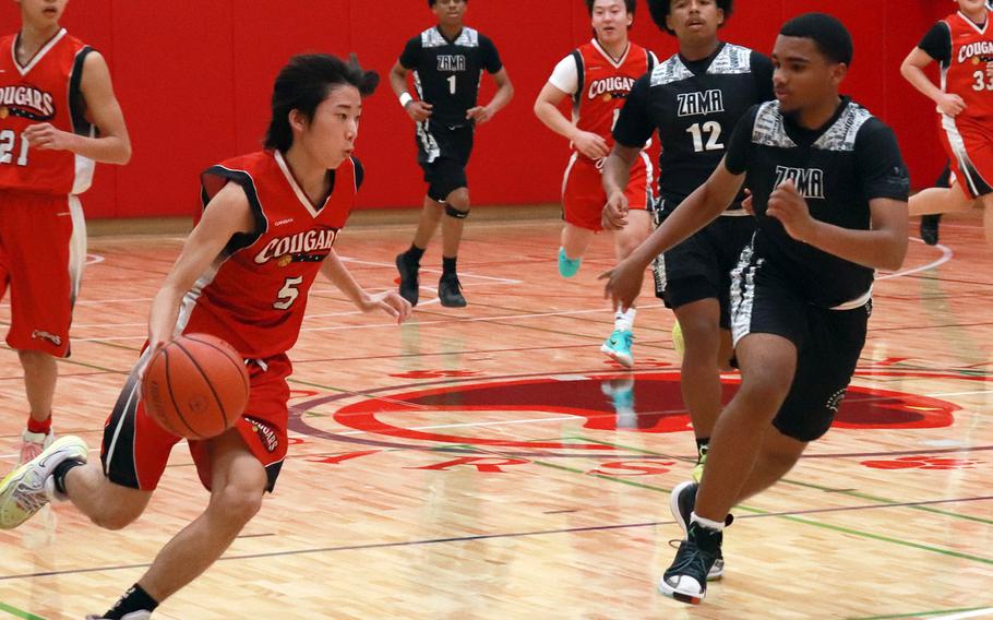 St. Maur's Kai Ginnane dribbles against Zama's Ryan Pena during Wednesday's Kanto Plain boys basketball game. The Trojans won 77-22.