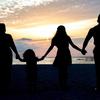A family hold hands while on a beach.