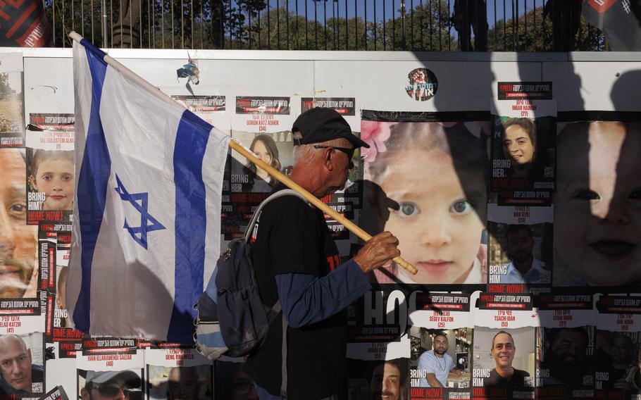 A man holding an Israeli flag walks by a wall covered with posters of Israeli hostages who were kidnapped by Hamas, in Jerusalem on Monday.