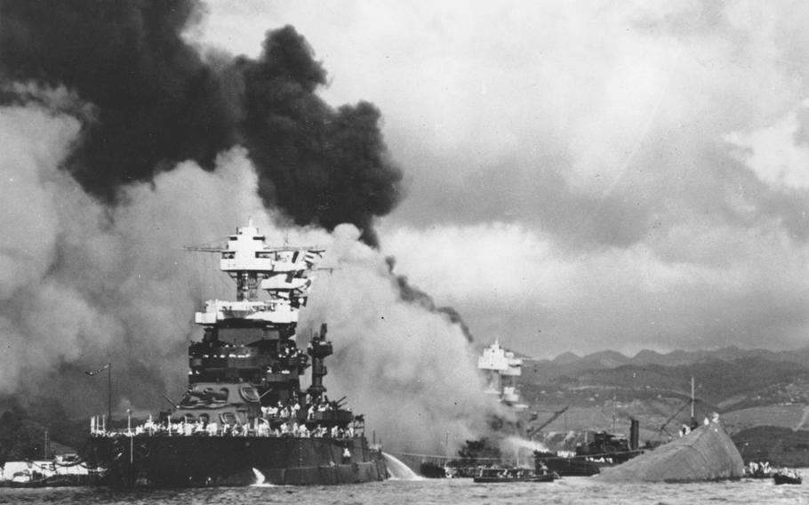 In this Dec. 7, 1941, file photo, part of the hull of the capsized USS Oklahoma is seen at right as the battleship USS West Virginia, center, begins to sink after suffering heavy damage, while the USS Maryland, left, is still afloat in Pearl Harbor, Oahu, Hawaii.