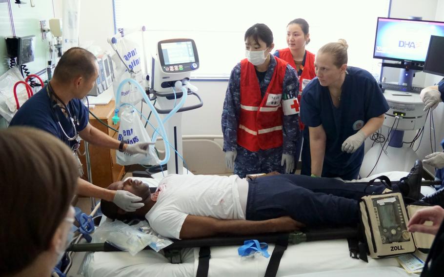 An actor taking part in an earthquake-response drill is handled by an intensive care unit at Yokosuka Naval Base, Japan, Wednesday, May 17, 2023.