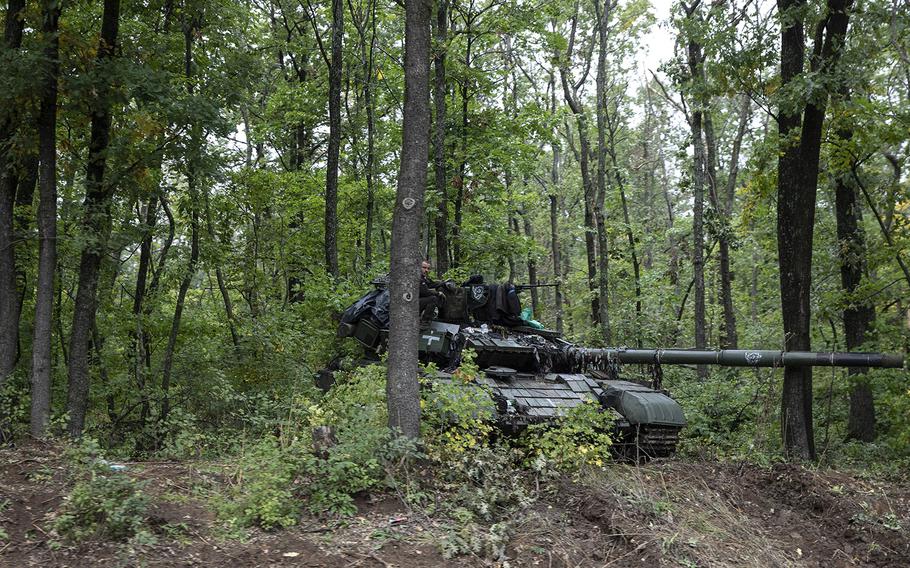 A Ukrainian soldier by a Russian tank captured by Ukrainian forces in the woods in the outskirts of Kupiansk, Ukraine, on Sept. 16, 2022. 