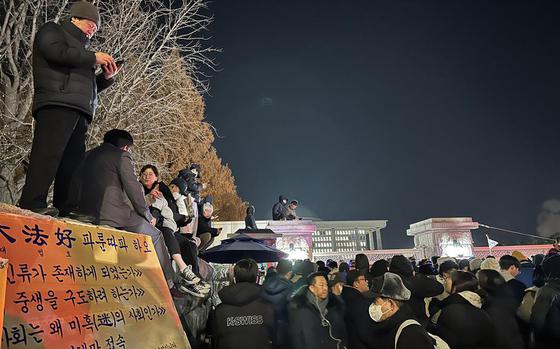 Activists and bystanders gather around a gate leading to the National Assembly building in Seoul, South Korea, Dec. 4, 2024.